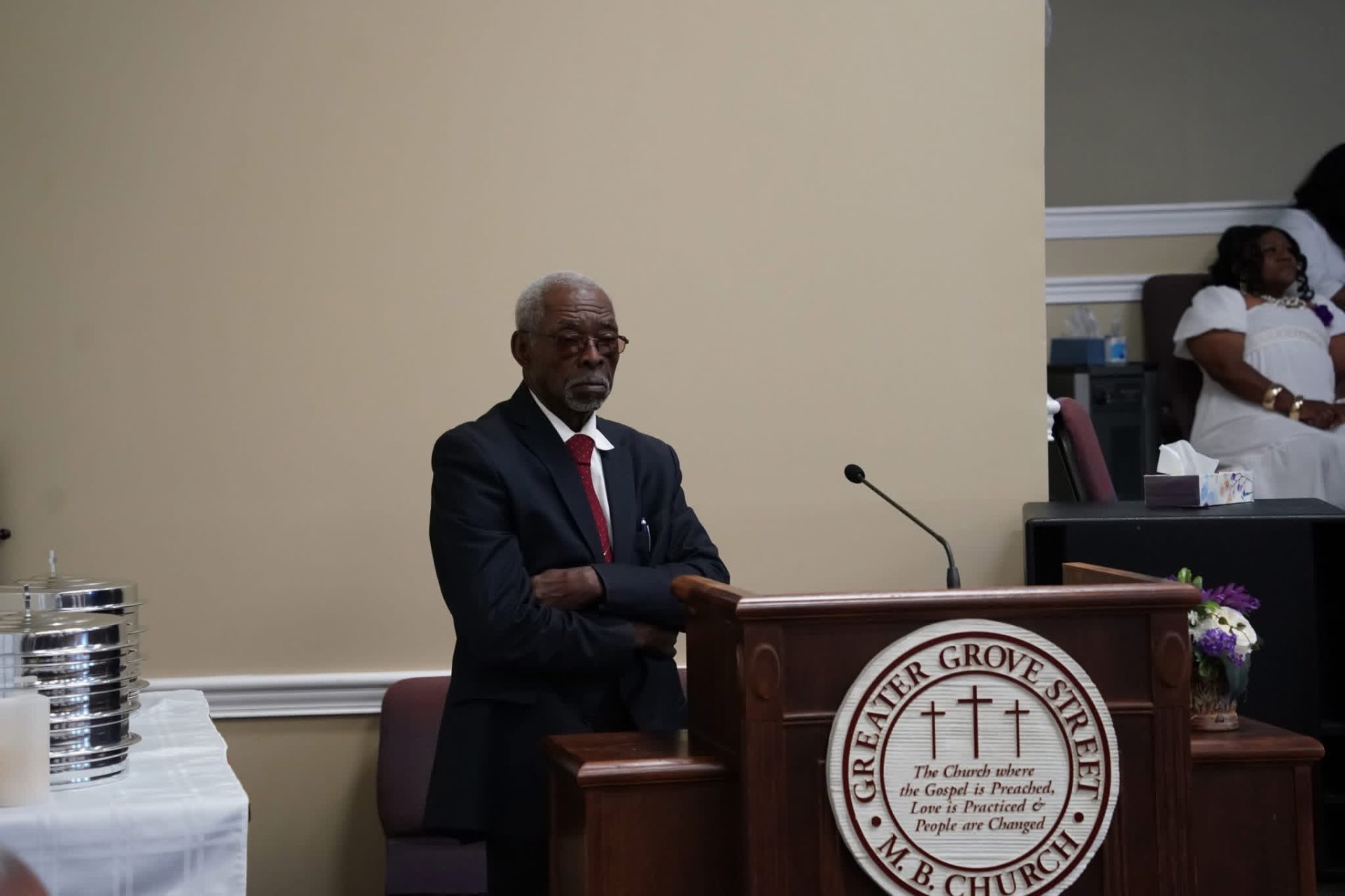 A church leader standing beside the Greater Grove Street pulpit and communion table